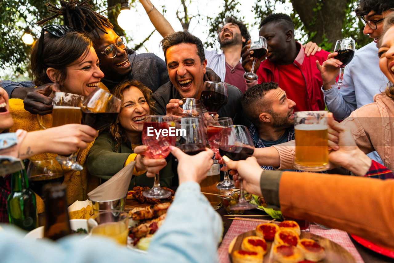 Group of people toasting with wine and beer - happy friends having fun outdoor