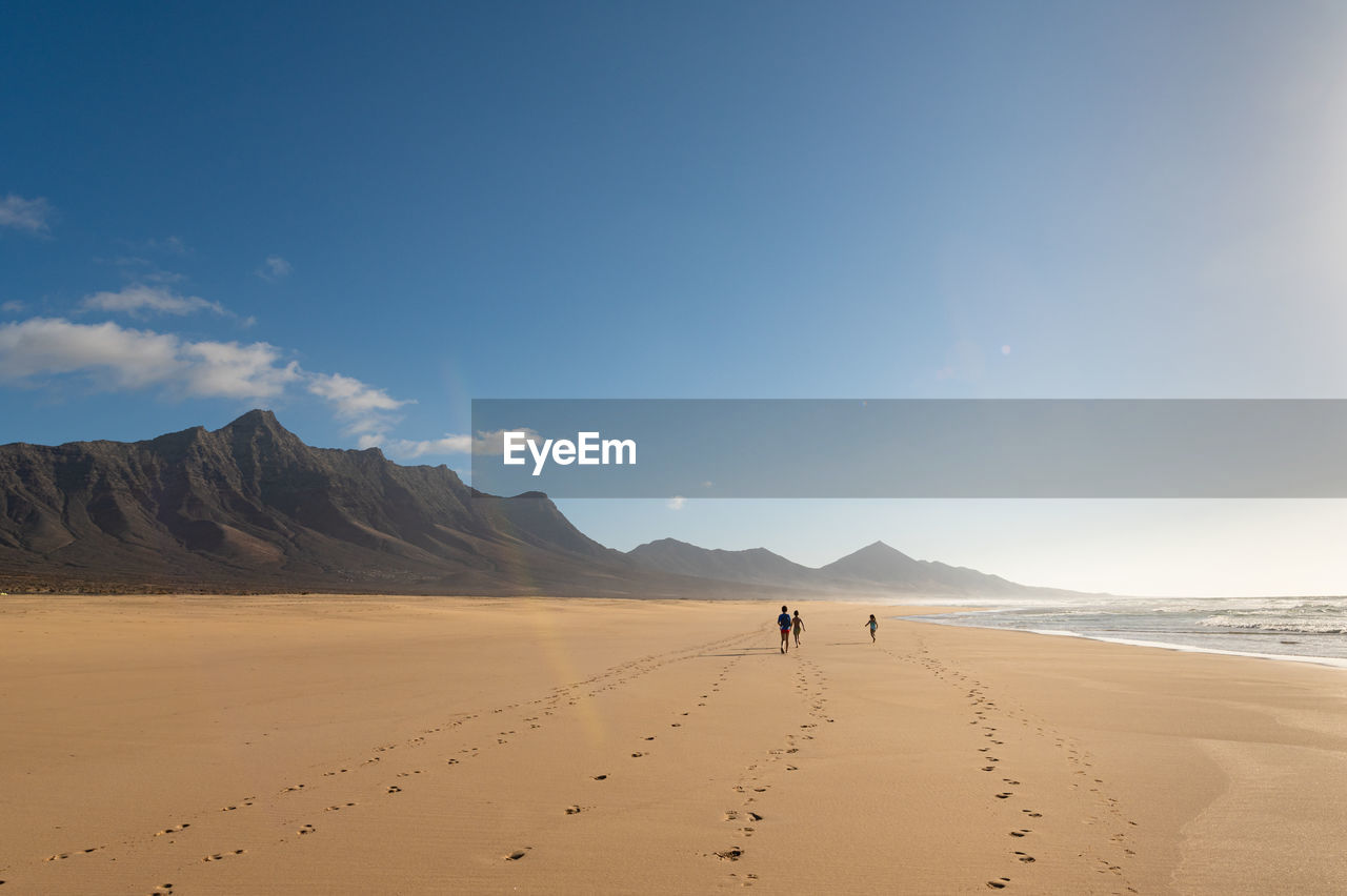 PEOPLE ON BEACH AGAINST SKY