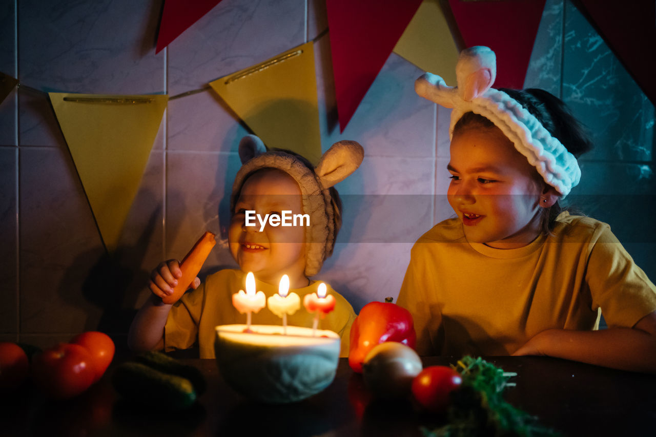 Vegetarian cake with candles birthday vegetables kids in bunny ears girl crying. high quality photo