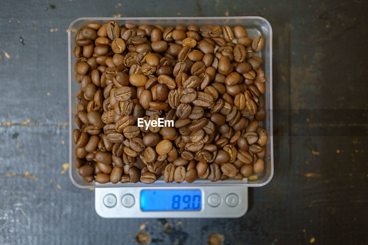 Close-up of roasted coffee beans in weight scale on table