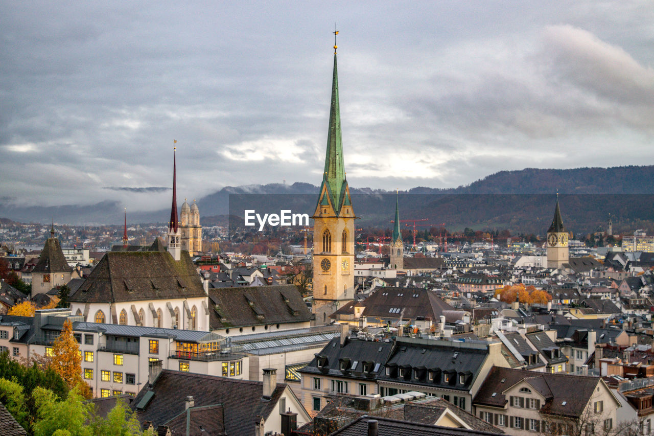 HIGH ANGLE VIEW OF TOWNSCAPE AGAINST CLOUDY SKY