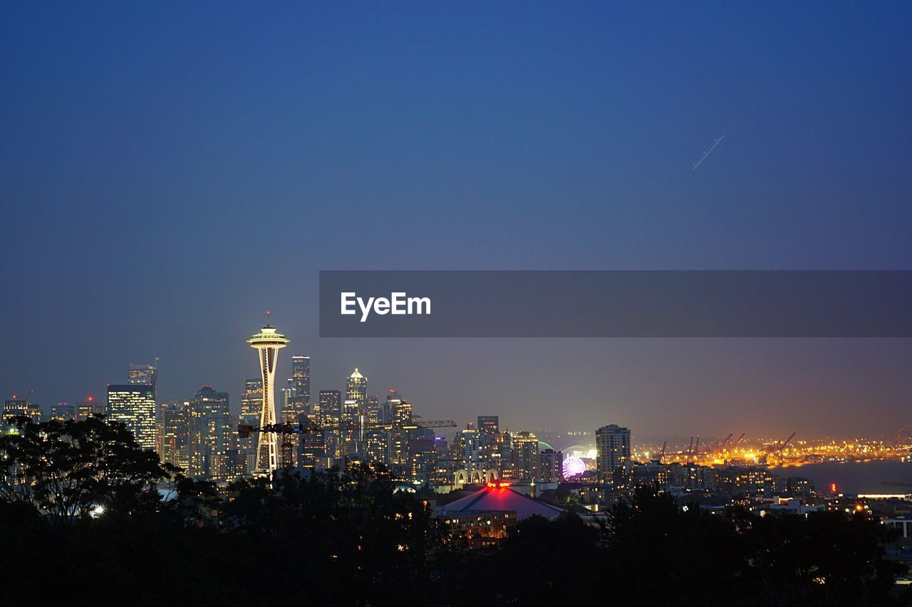 View of illuminated cityscape against blue sky