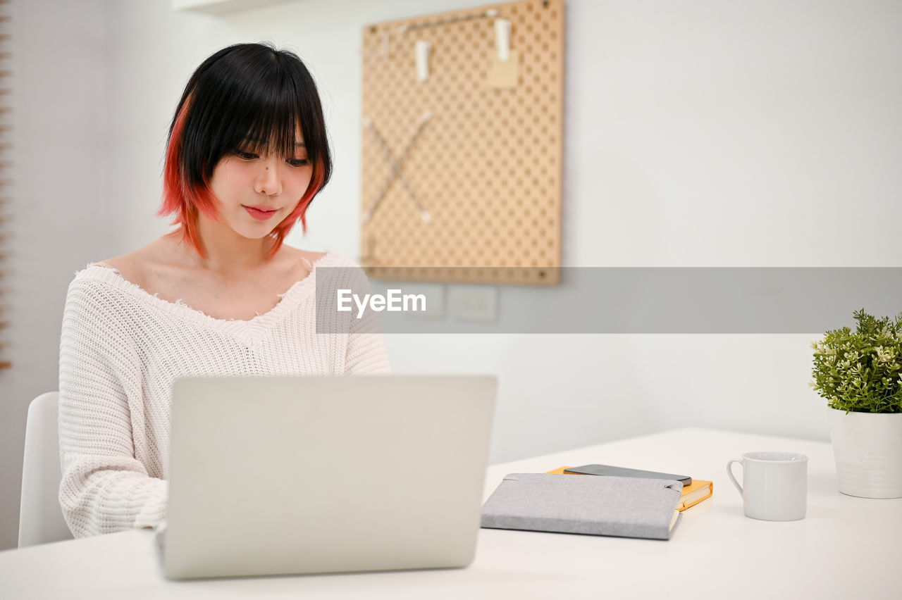 young woman using laptop while sitting at home