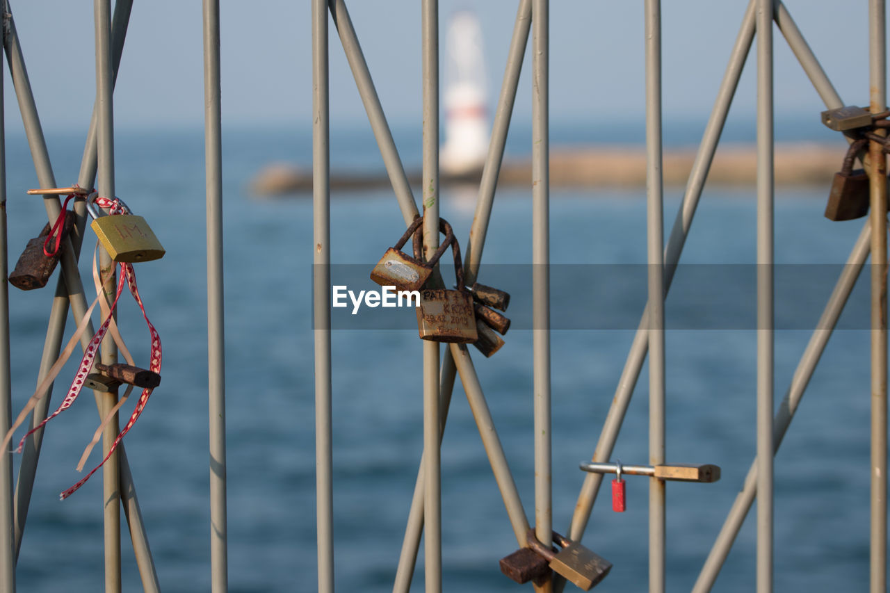 Close-up of rusty padlocks on railing against seascape