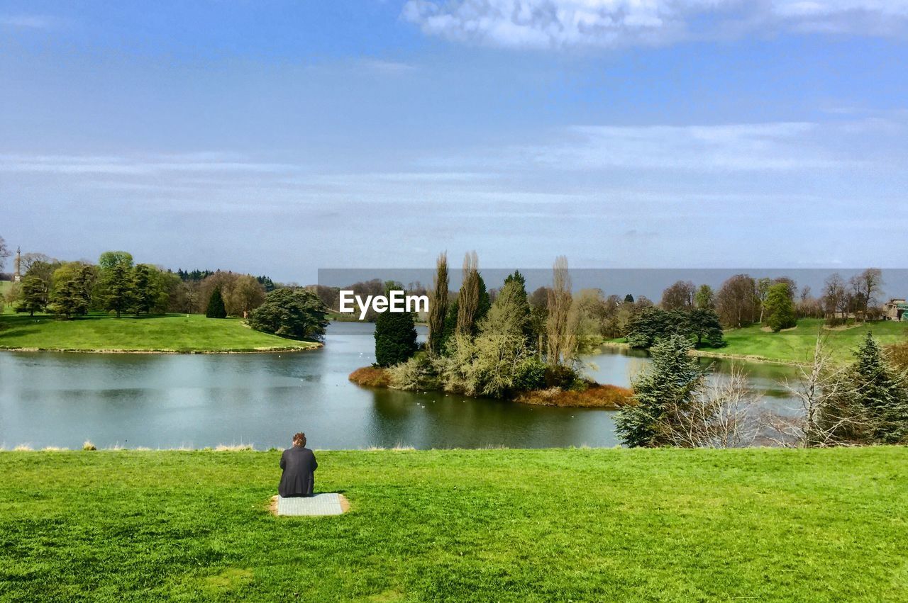 Rear view of man sitting at lakeshore