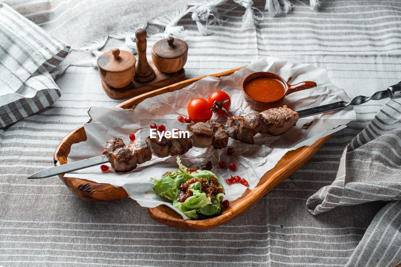 Barbecue with tomatoes and herbs on a wooden plate with paper