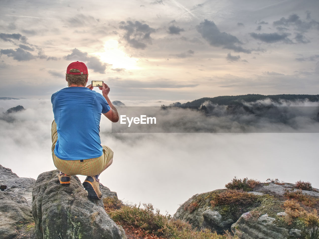 Man taking picture of amazing fall mountains on his phone in misty weather