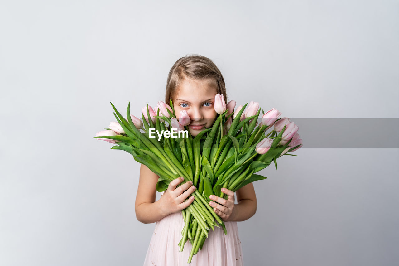 PORTRAIT OF GIRL HOLDING PLANT AGAINST WHITE BACKGROUND