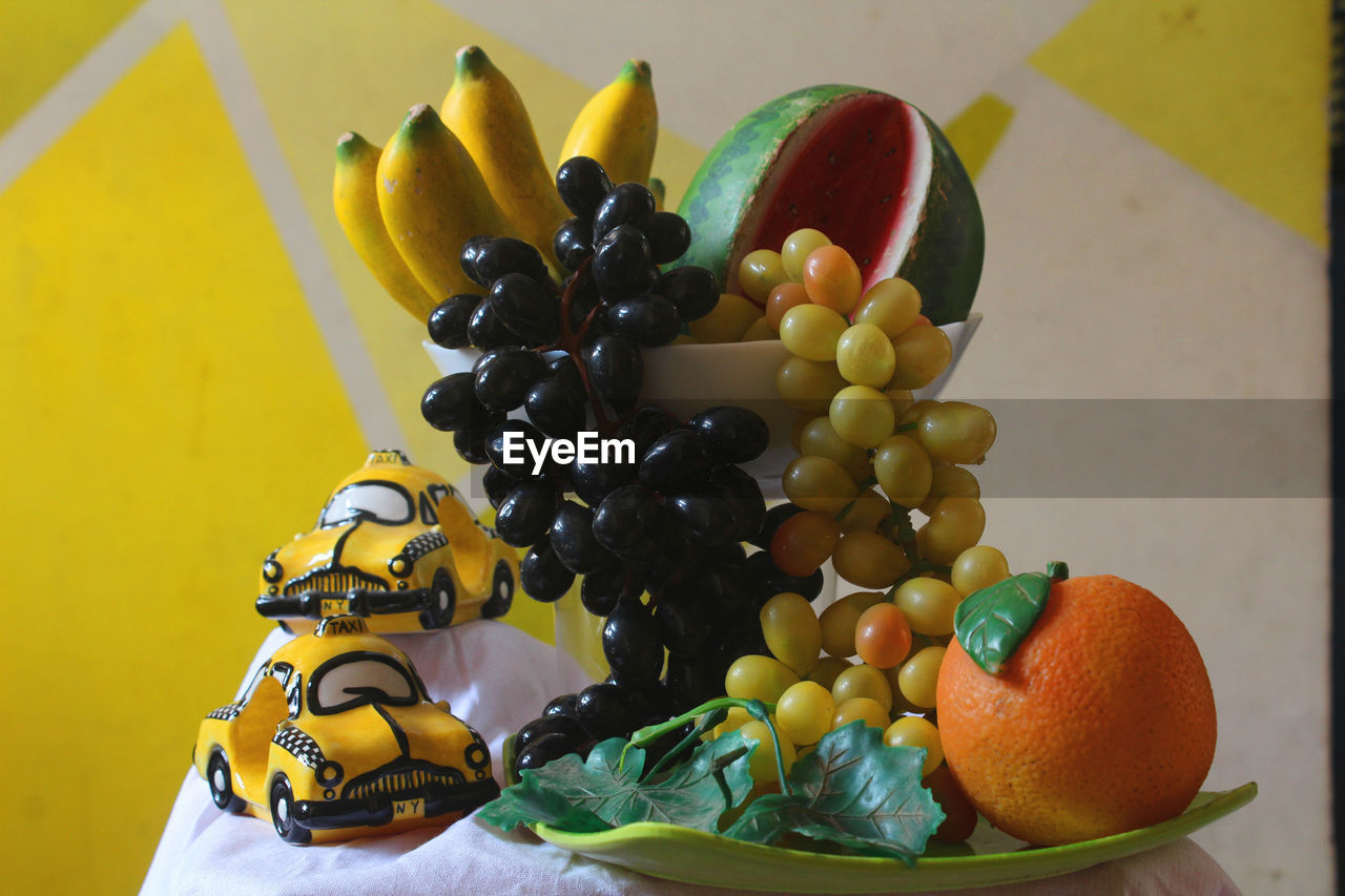 CLOSE-UP OF FRUITS ON TABLE AGAINST ORANGE WALL
