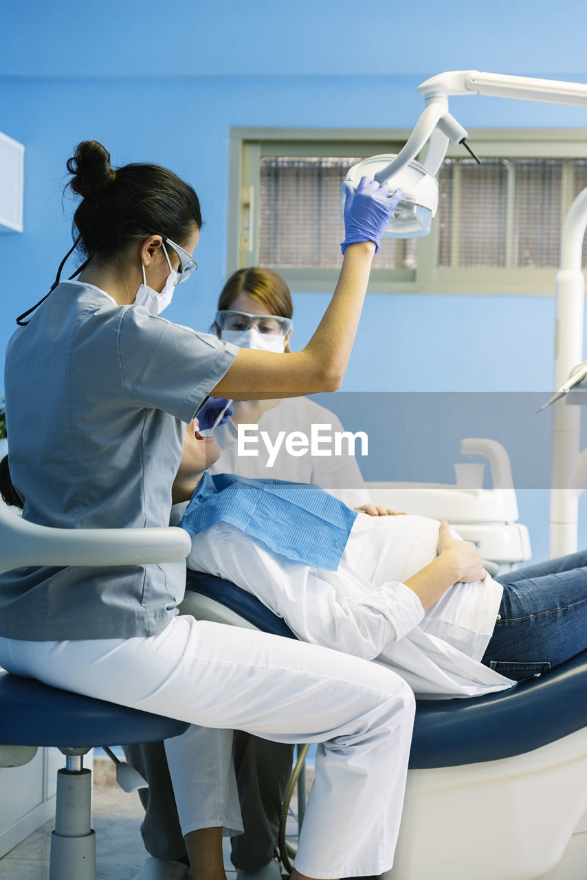 Dentists examining pregnant woman in clinic