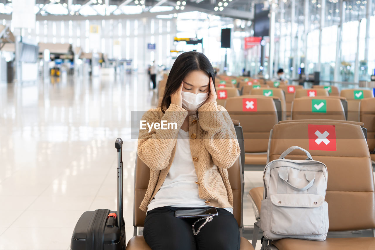 Woman wearing mask sitting at airport lounge