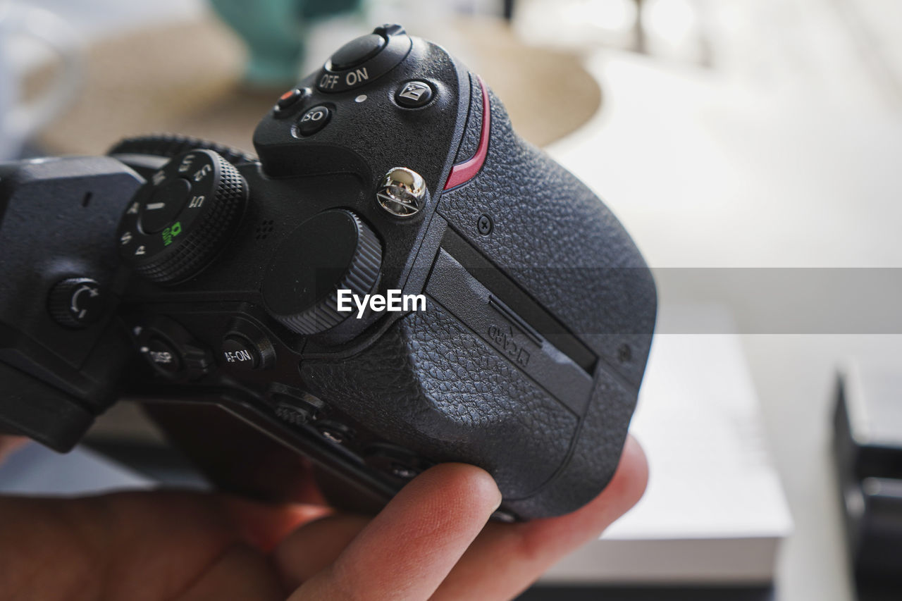 hand, camera, technology, holding, one person, close-up, focus on foreground, digital slr, black, indoors, occupation, adult