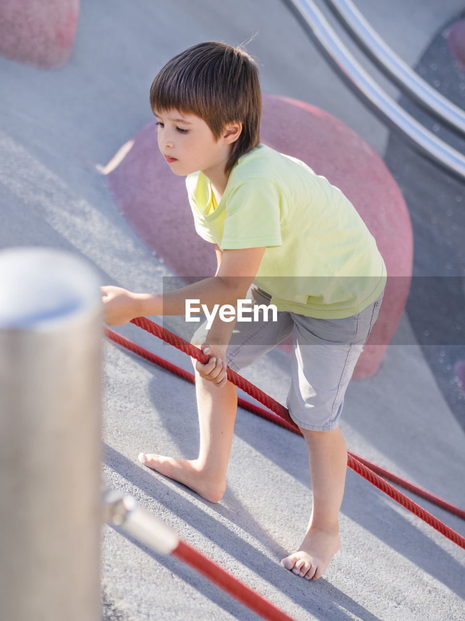 Boy climbs up a slope of modern children's sportsground. kid overcomes fear and learn new things. 