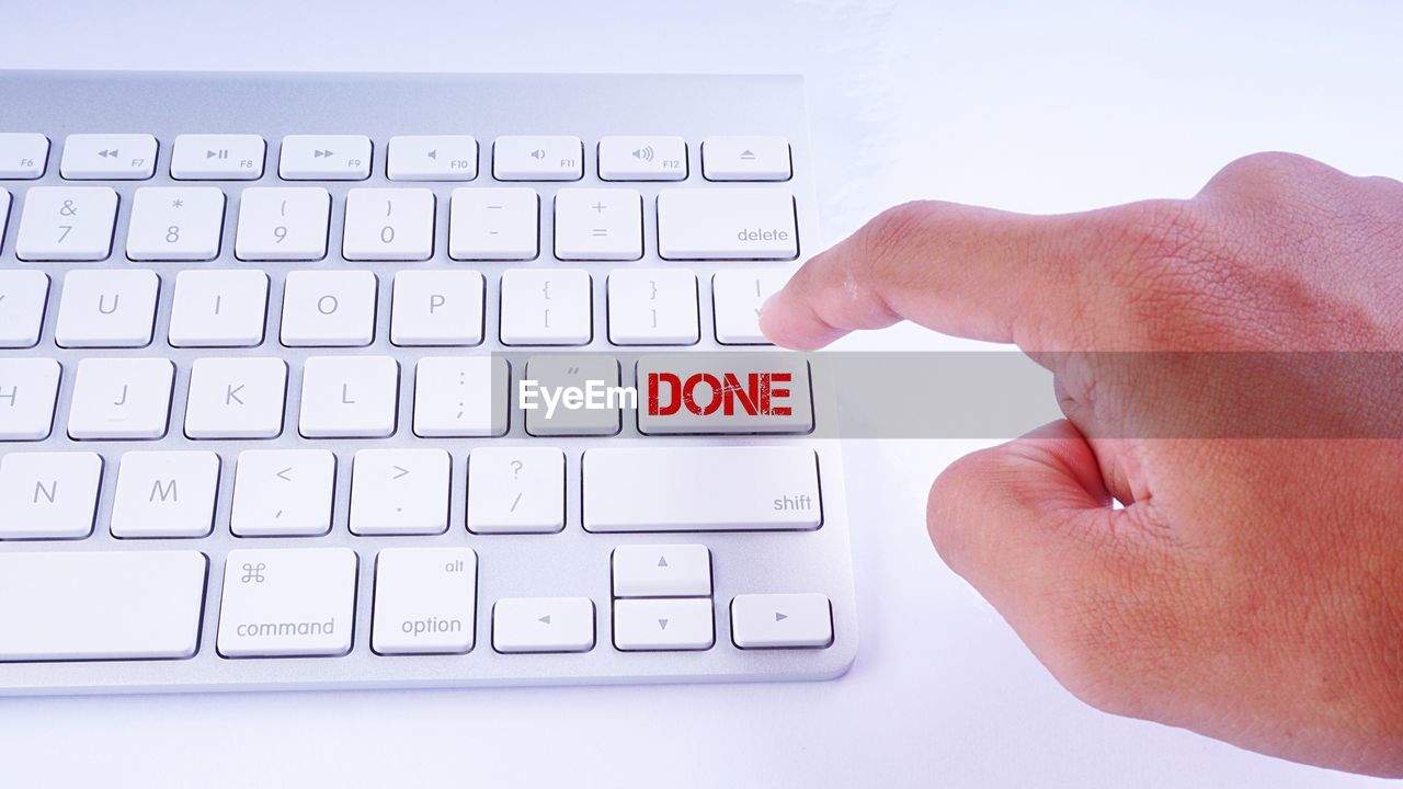 Cropped hand pressing done key on computer keyboard at table