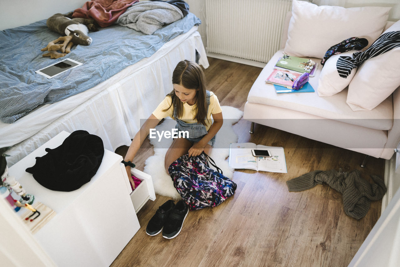 Caucasian girl packing bag in bedroom at home