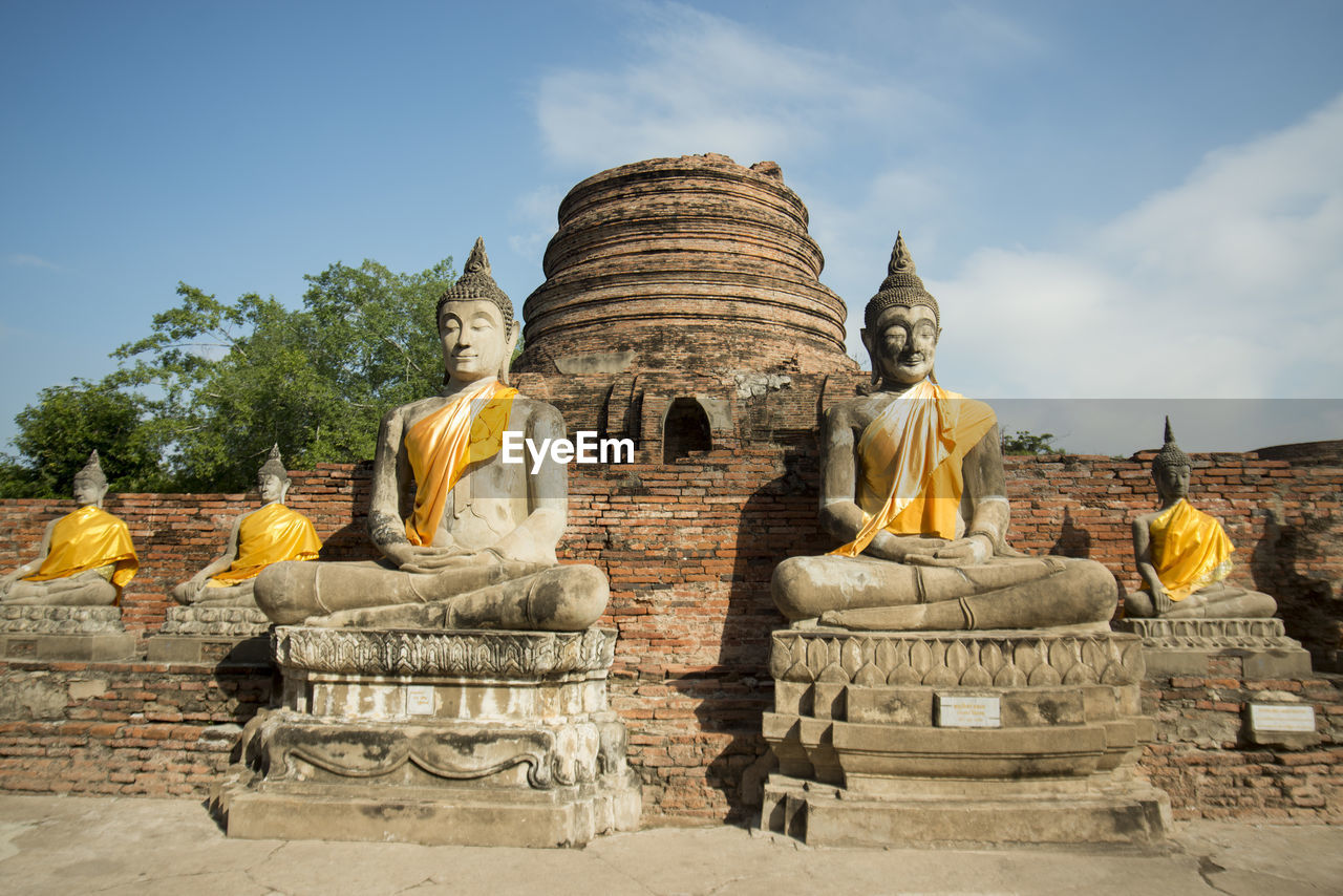 Buddha statues outside temple against blue sky