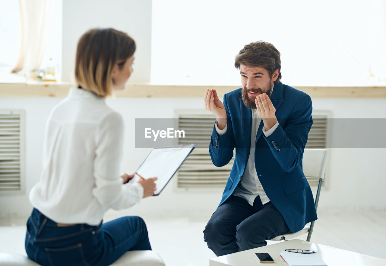 Young man sitting in front of woman