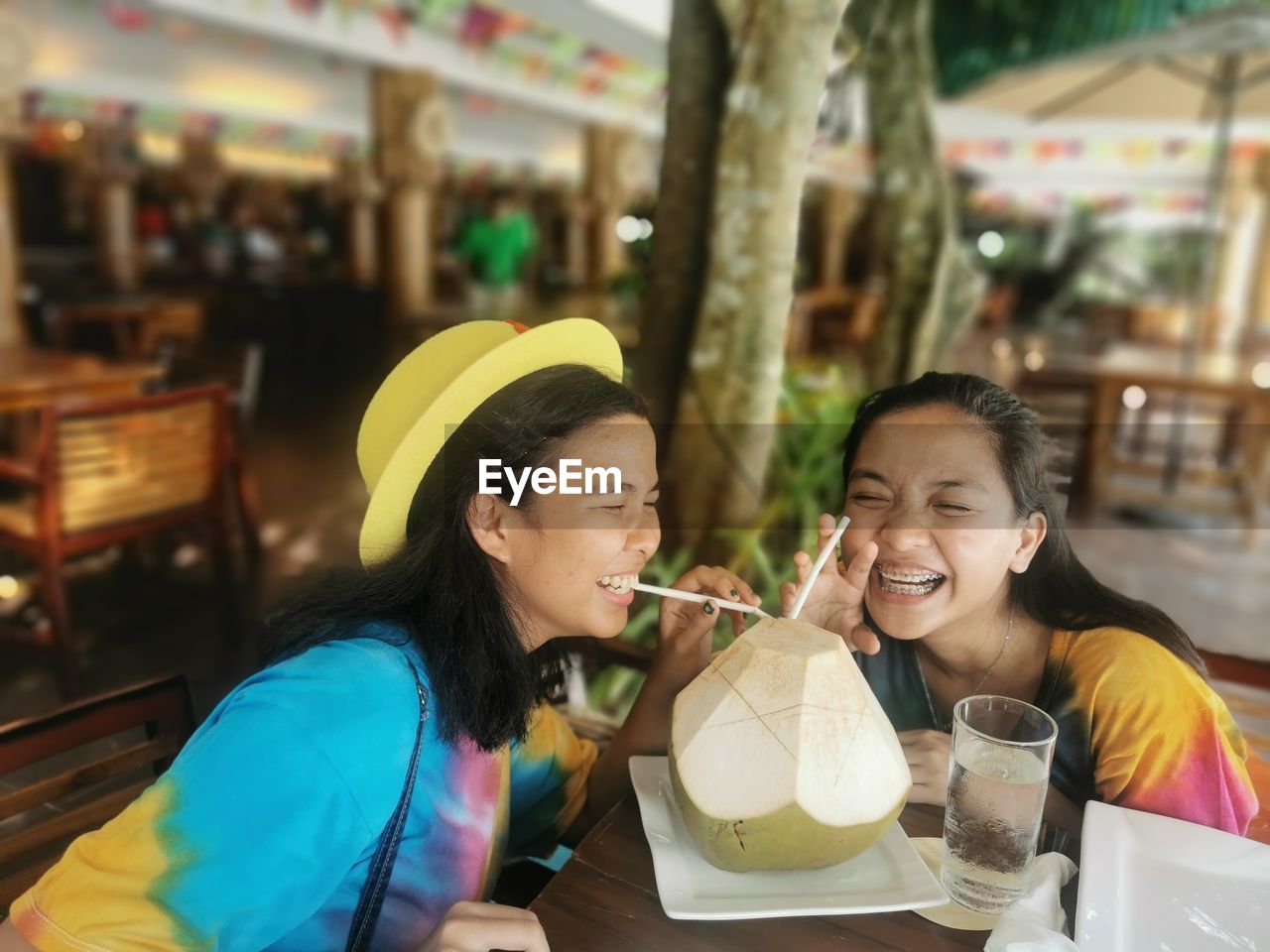 Sisters sharing coconut drink