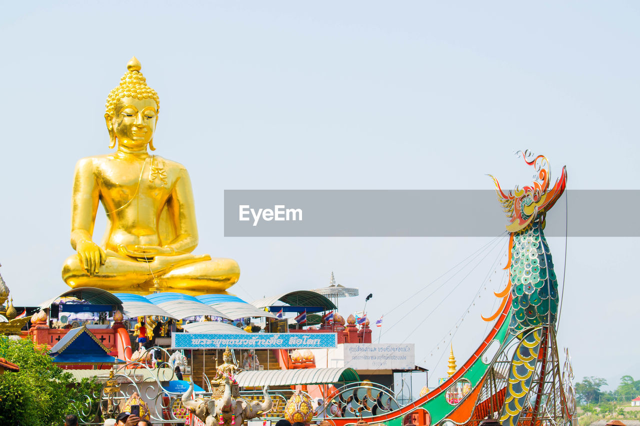 Low angle view of statue against temple building against sky