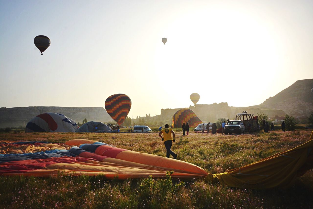 Hot air balloons on field against clear sky