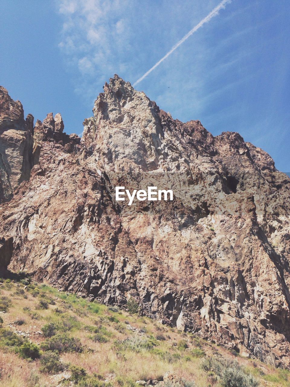 Jagged mountain peak with jet trail