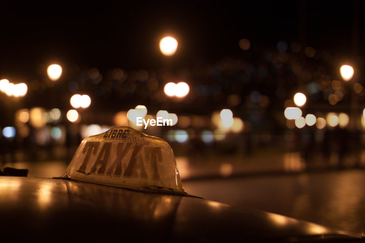 Taxi sign with lights in the background