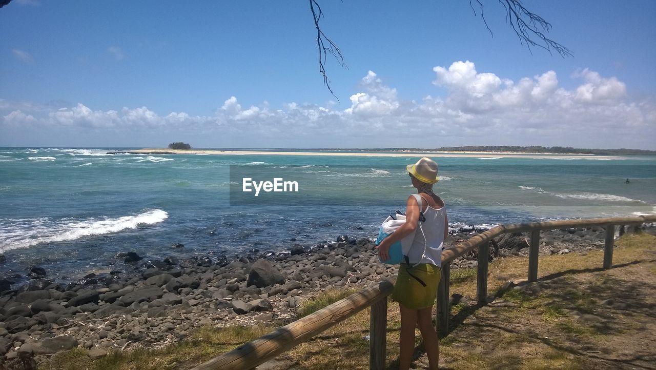 Rear view of woman overlooking calm sea