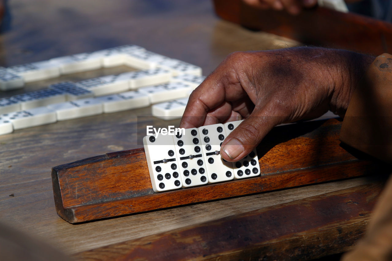 Cropped hand holding dominoes on wooden stick