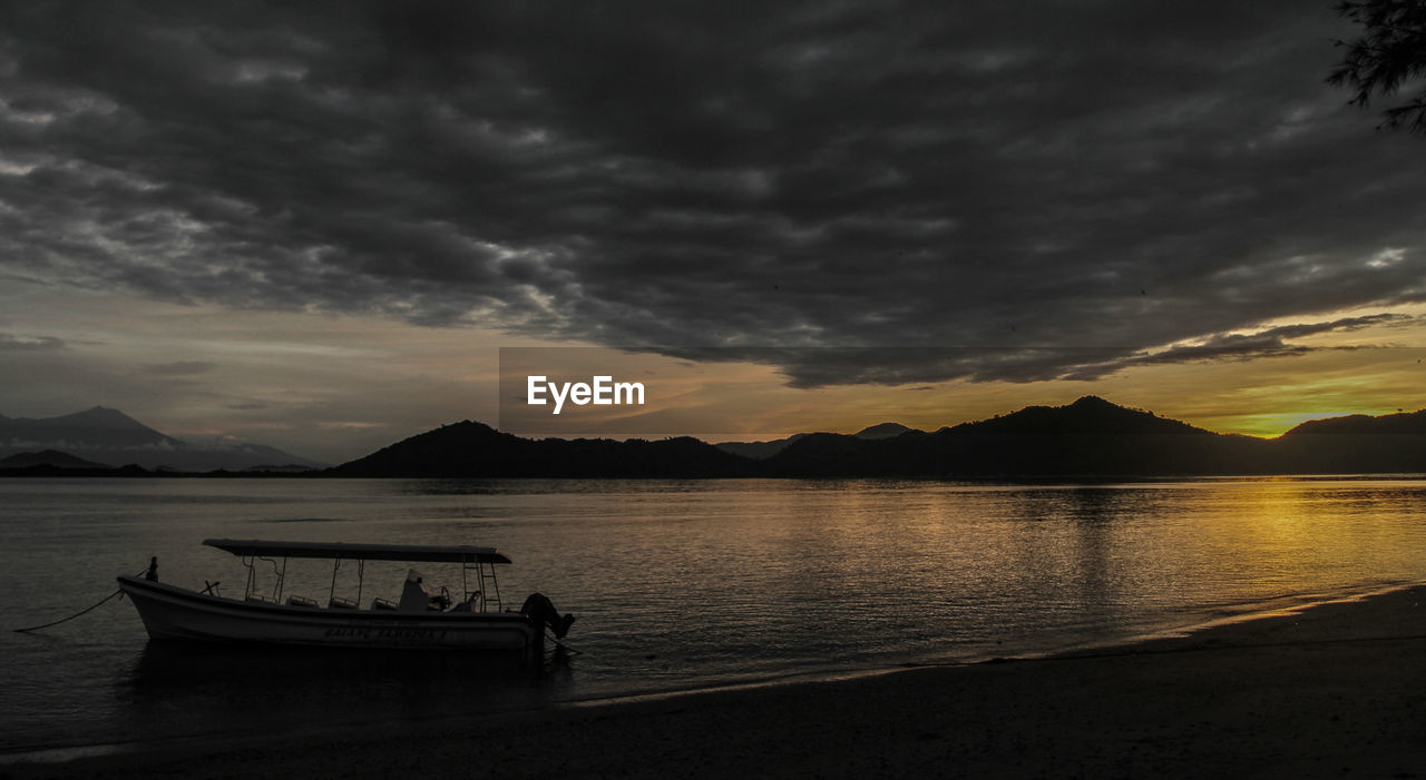 Silhouette boat in calm sea at sunset