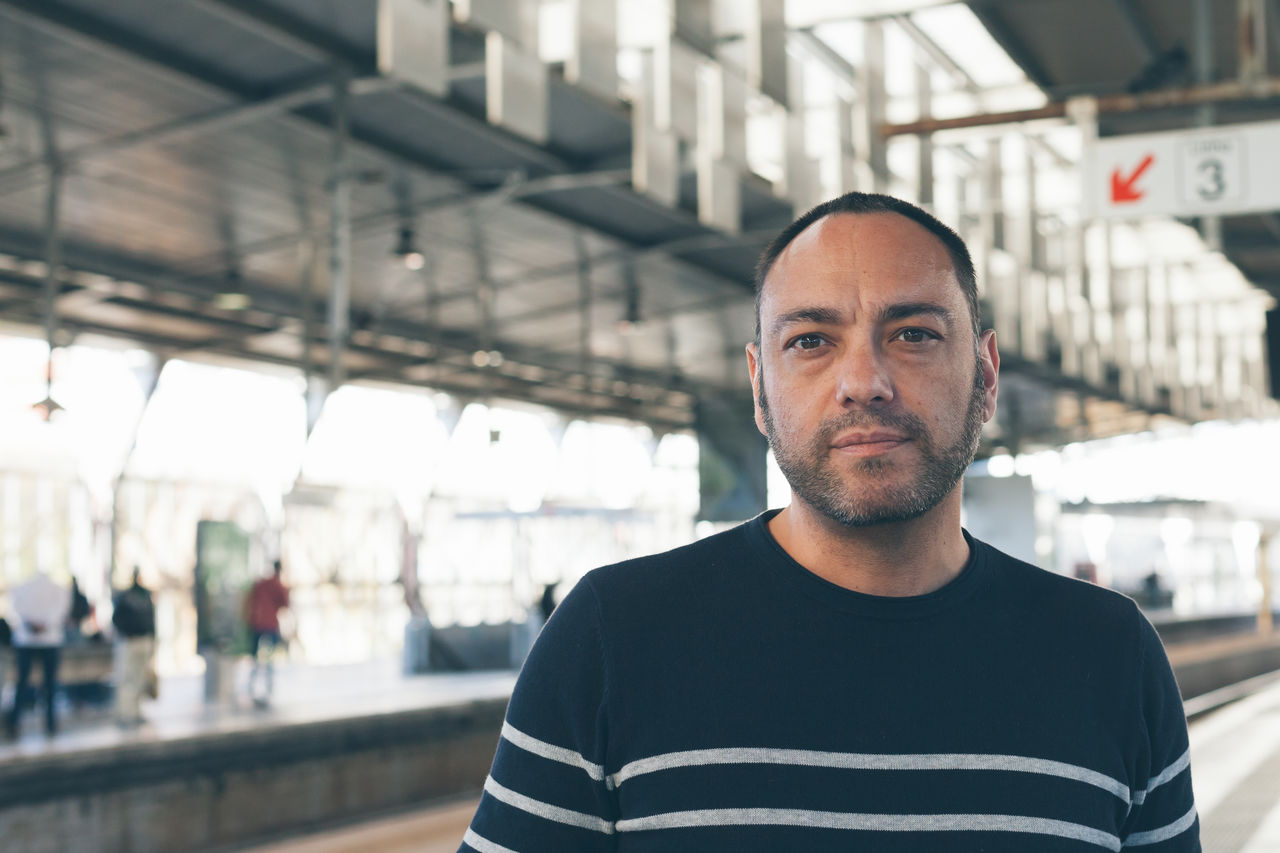 Portrait of mid adult man standing on railroad station platform