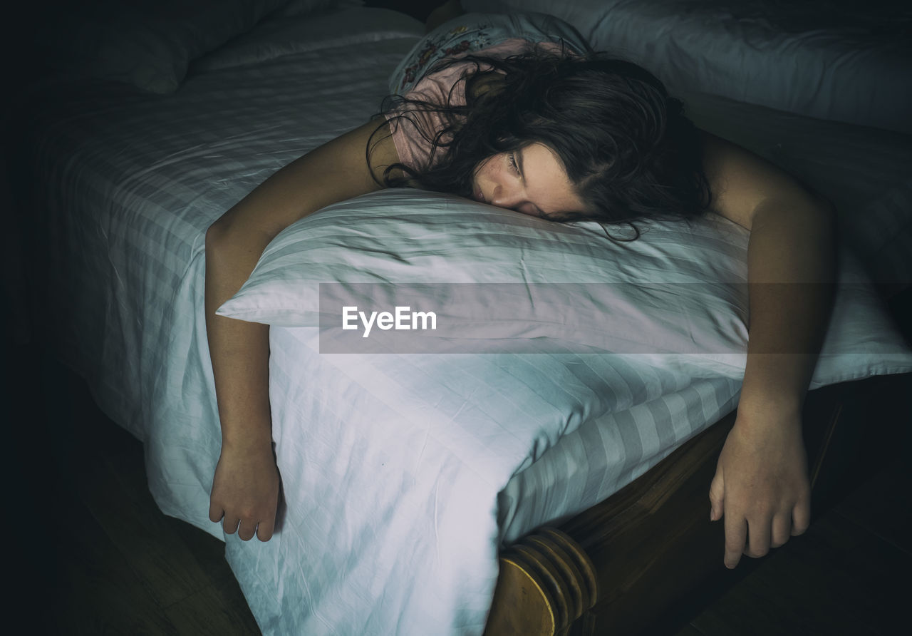 Girl looking away while lying on bed at home