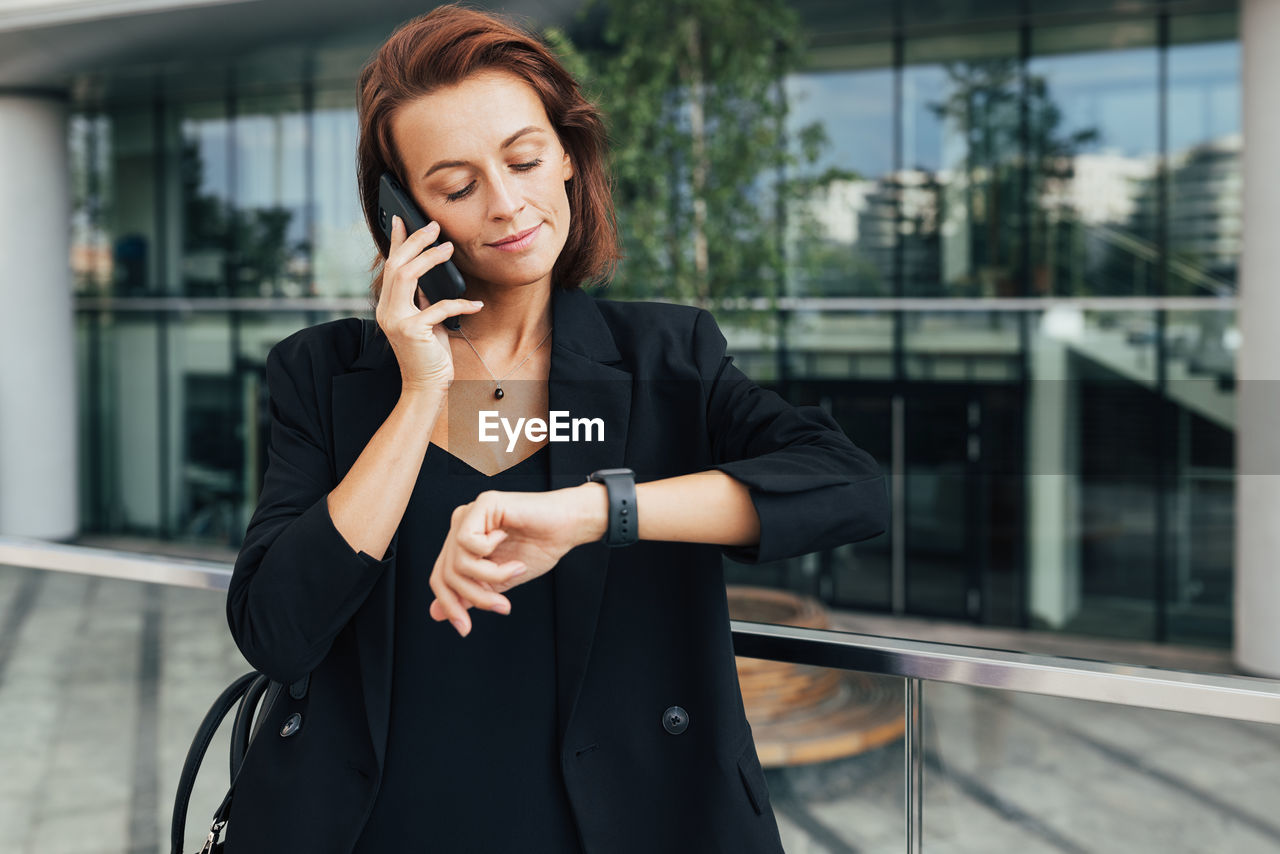 portrait of young businesswoman standing against building