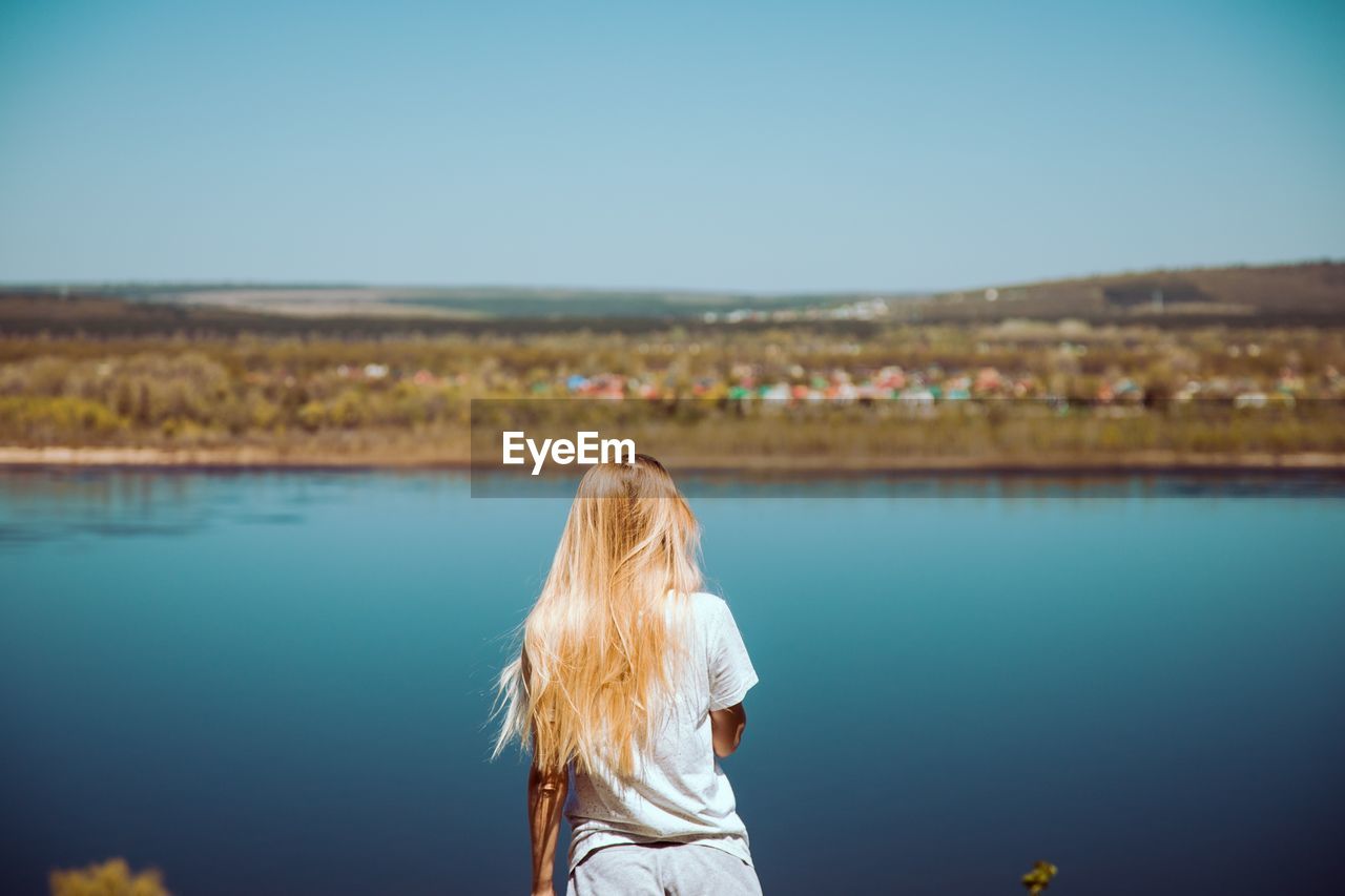 Rear view of woman standing against river