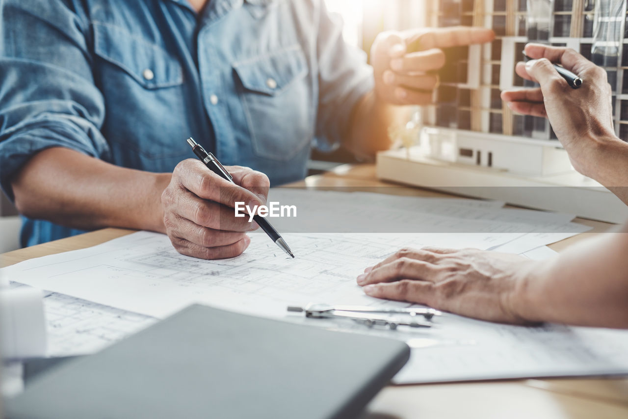 Cropped hands of architects working on blueprints