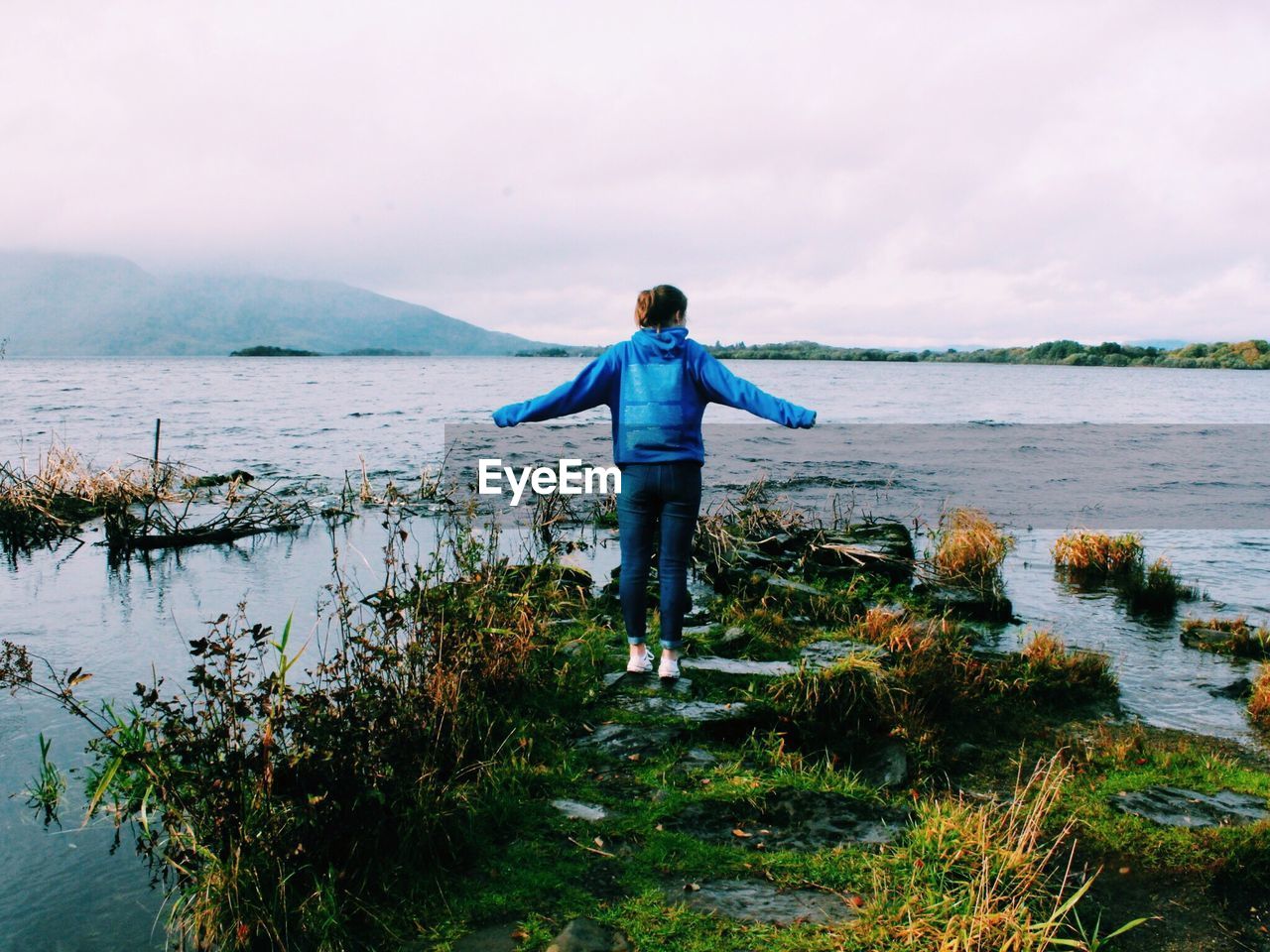 Full length of woman standing by lake against sky