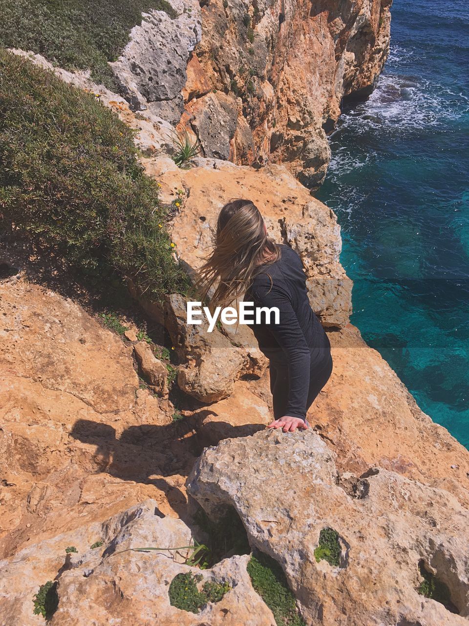 High angle view of woman standing on rock against sea at beach