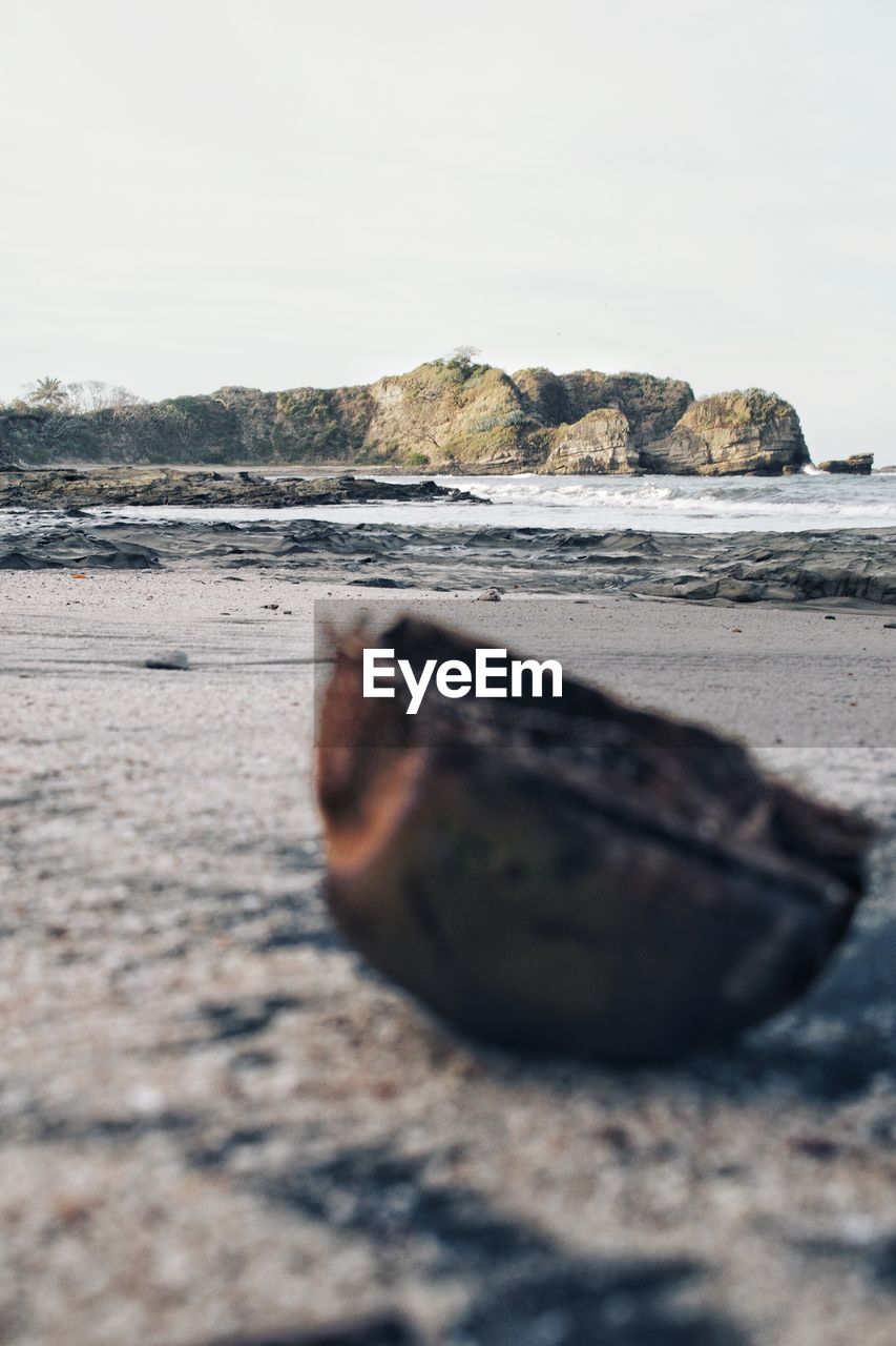 CLOSE-UP OF ROCKS ON BEACH AGAINST CLEAR SKY