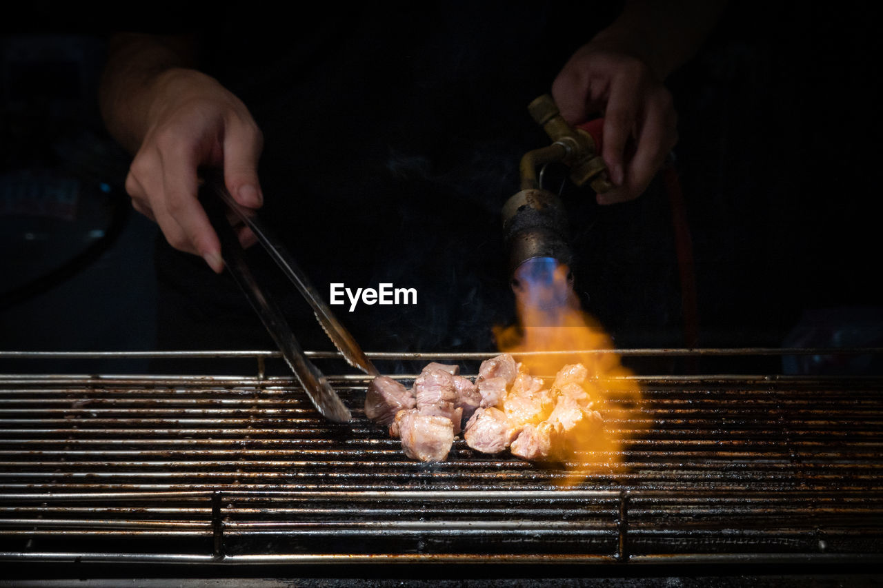 Cropped hand of man preparing food, fire taipei dice beef.