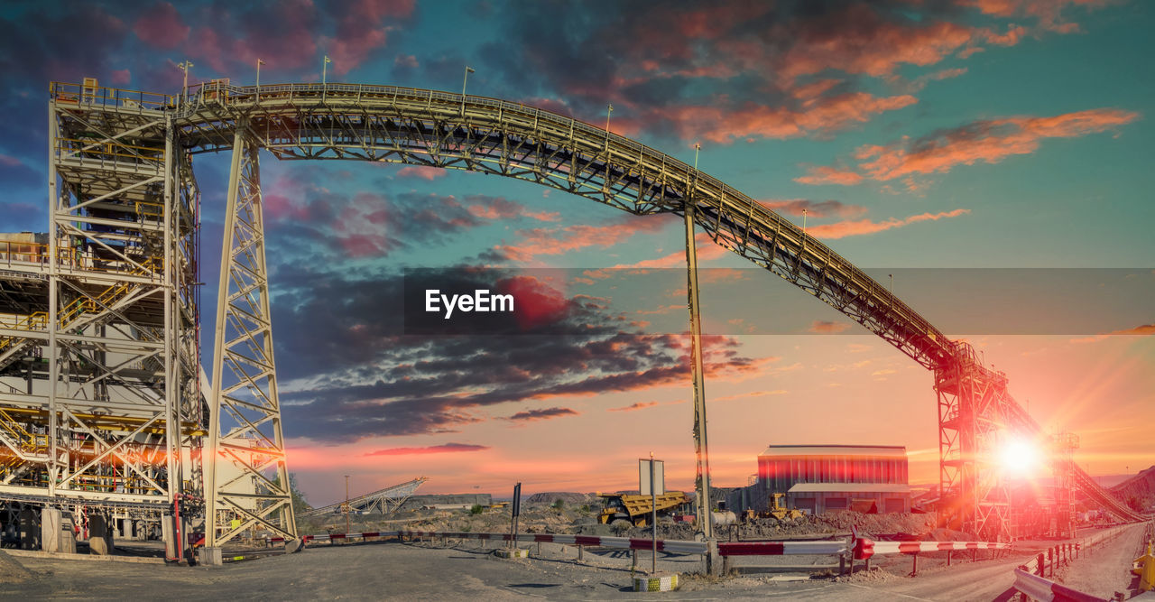 LOW ANGLE VIEW OF ROLLERCOASTER AGAINST SKY AT SUNSET