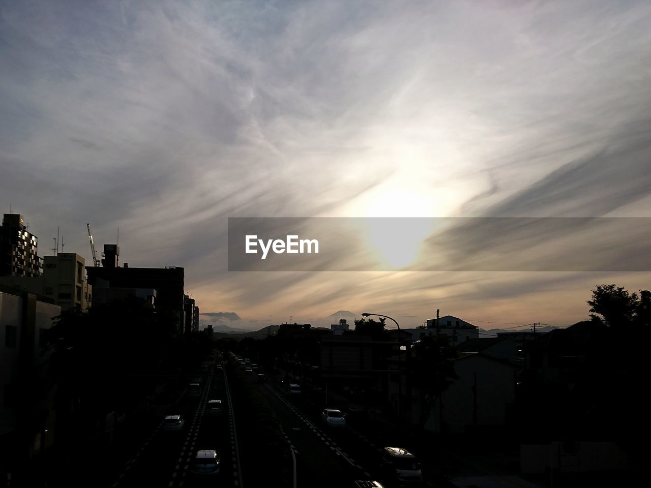 HIGH ANGLE VIEW OF STREET AMIDST BUILDINGS AGAINST SKY