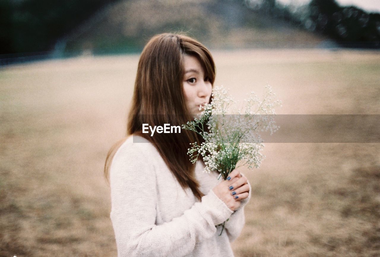 Young woman smelling flowers on field