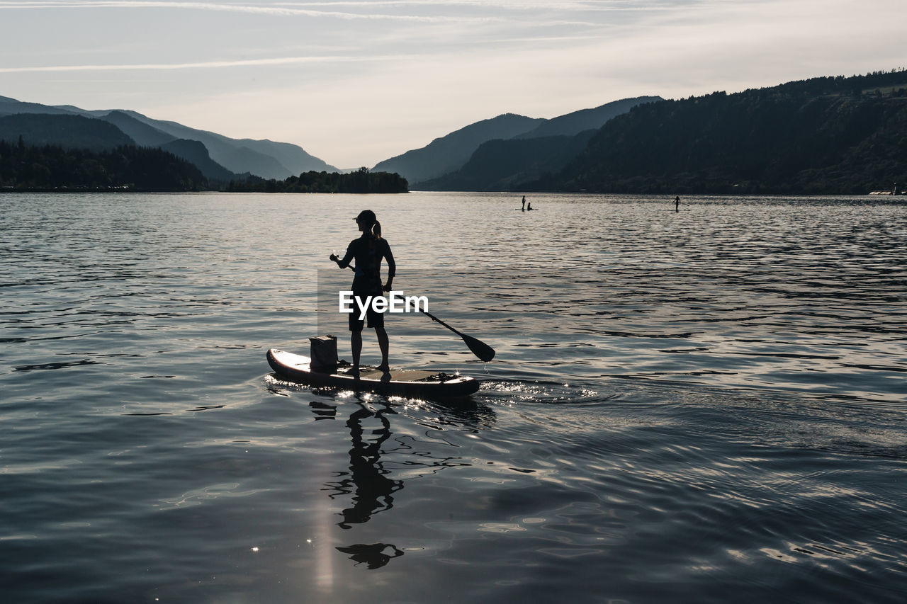 A young woman paddles a sup on the columbia river during a sunny day.