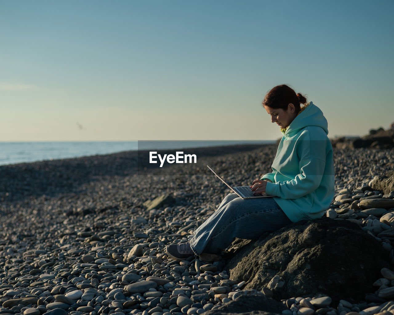 Caucasian woman working freelance on laptop on the beach