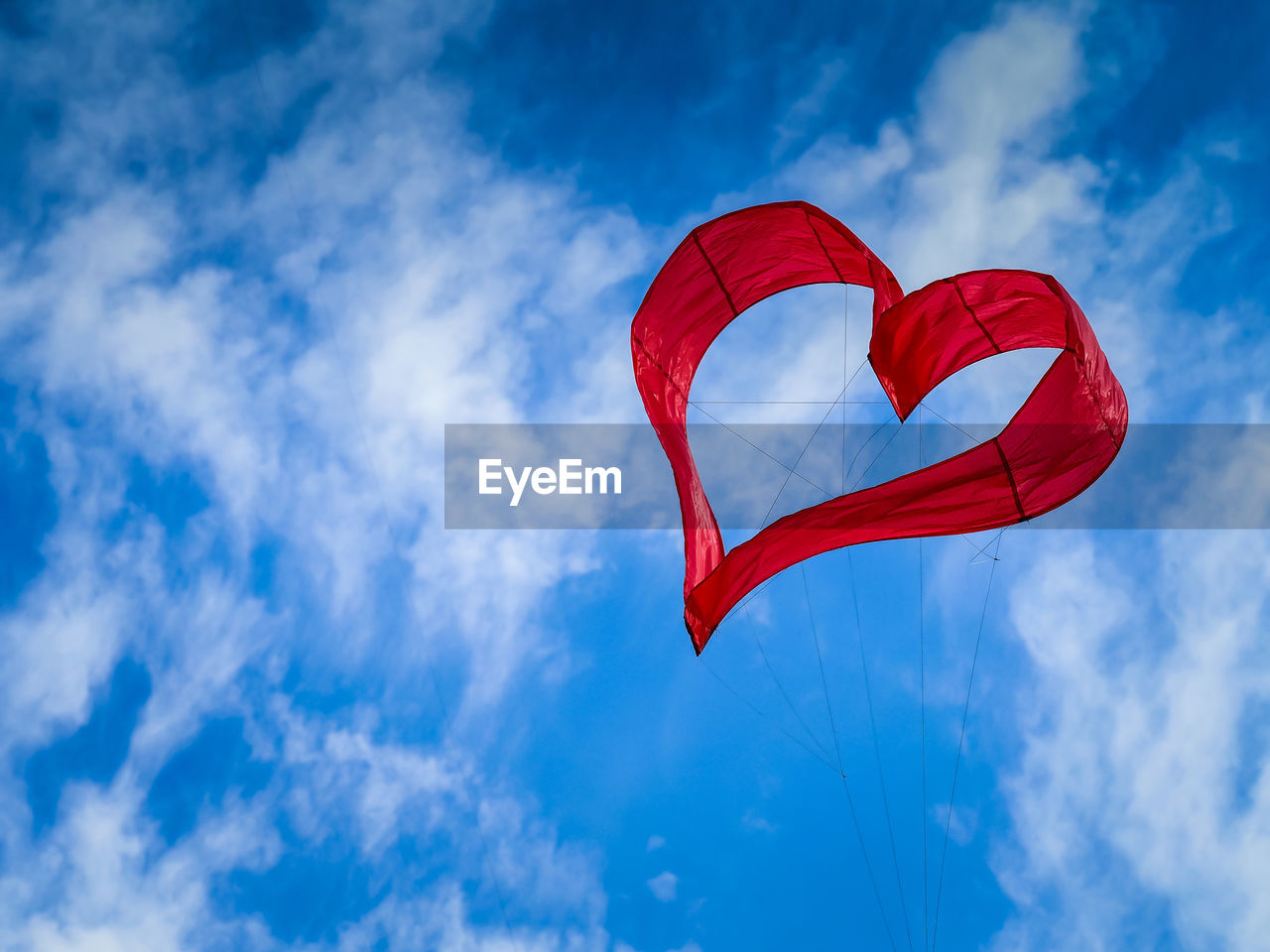 Low angle view of heart shape kite flying against sky