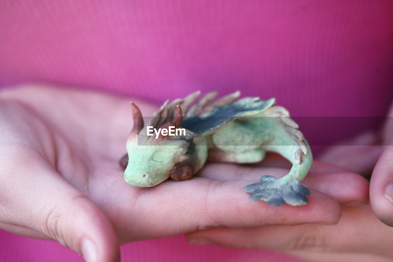 Midsection of woman holding dragon clay sculpture