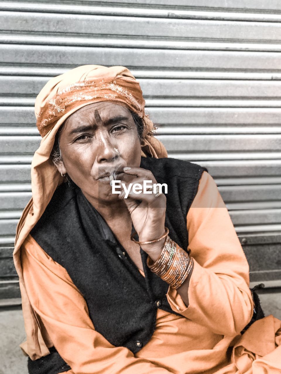 Portrait of woman smoking bidi against shutter