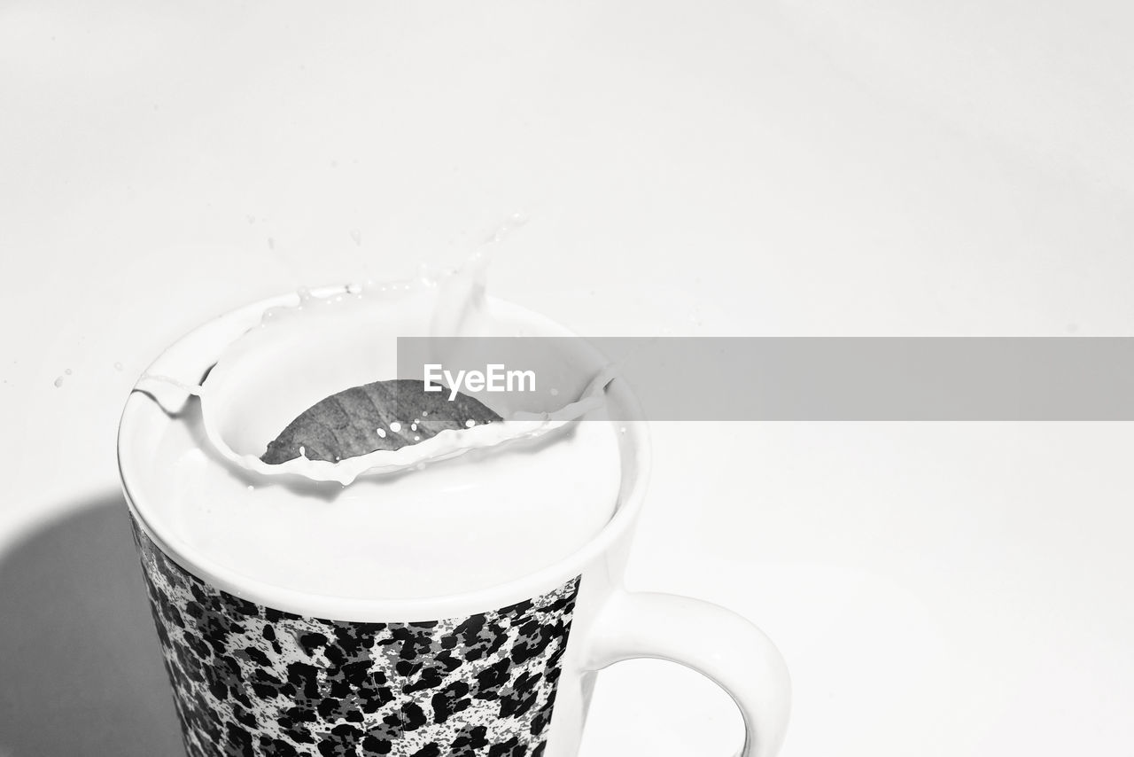 Close-up of cookie in cup of milk against white background