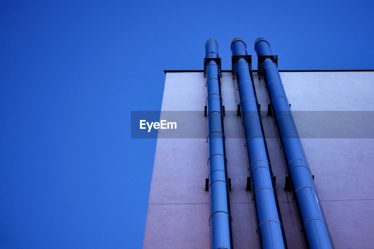 LOW ANGLE VIEW OF SMOKE STACKS AGAINST BLUE SKY