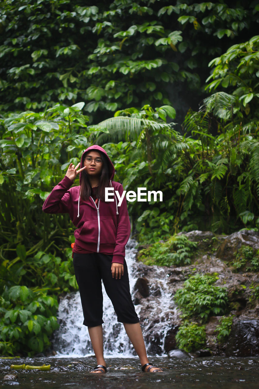 Full length of young woman standing against plants