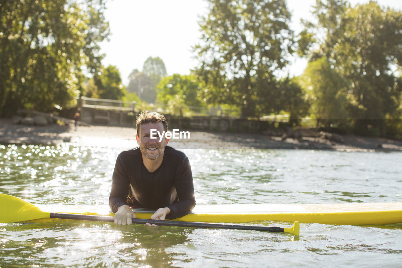 Portrait of smiling man paddleboarding on river